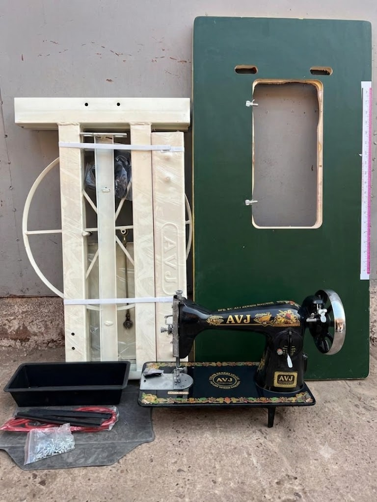 AVJ branded black and gold domestic sewing machine with green table top, wooden export crate, accessories tray and spare parts