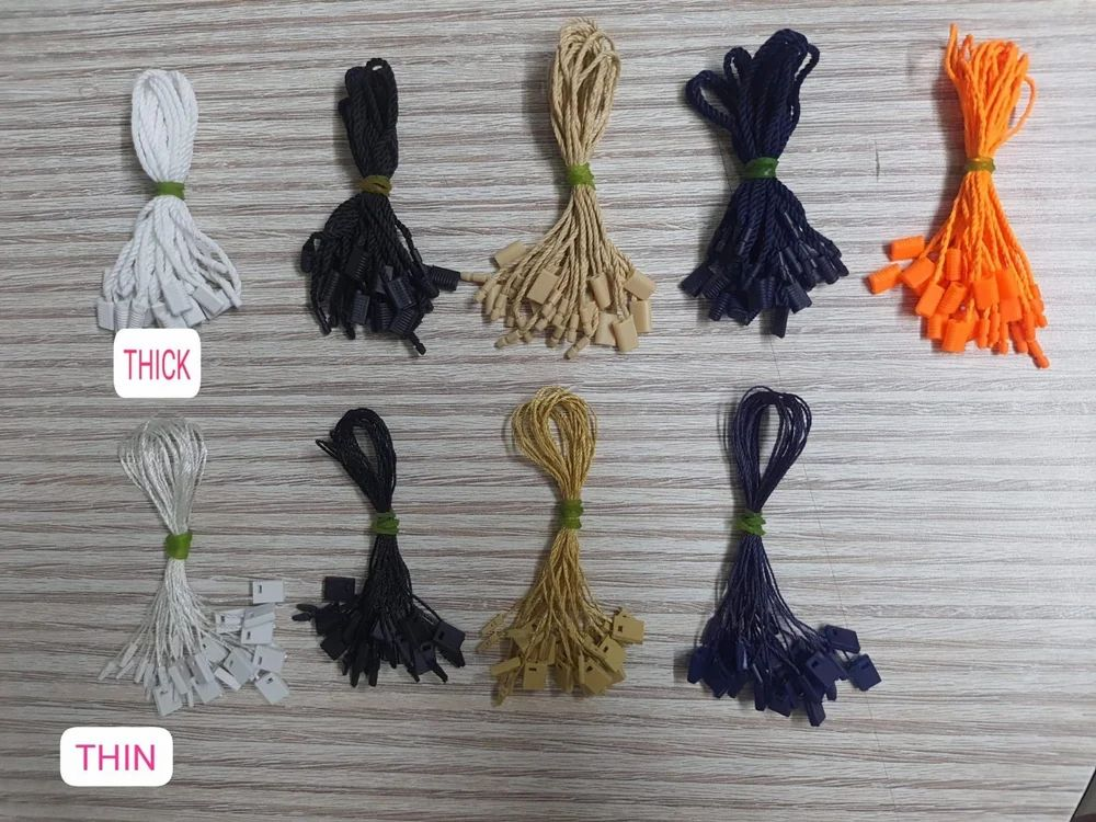 Garment hang tag strings and loop pins in thick and thin varieties, shown in white, black, beige, navy, orange, silver and gold with moulded plastic tag ends